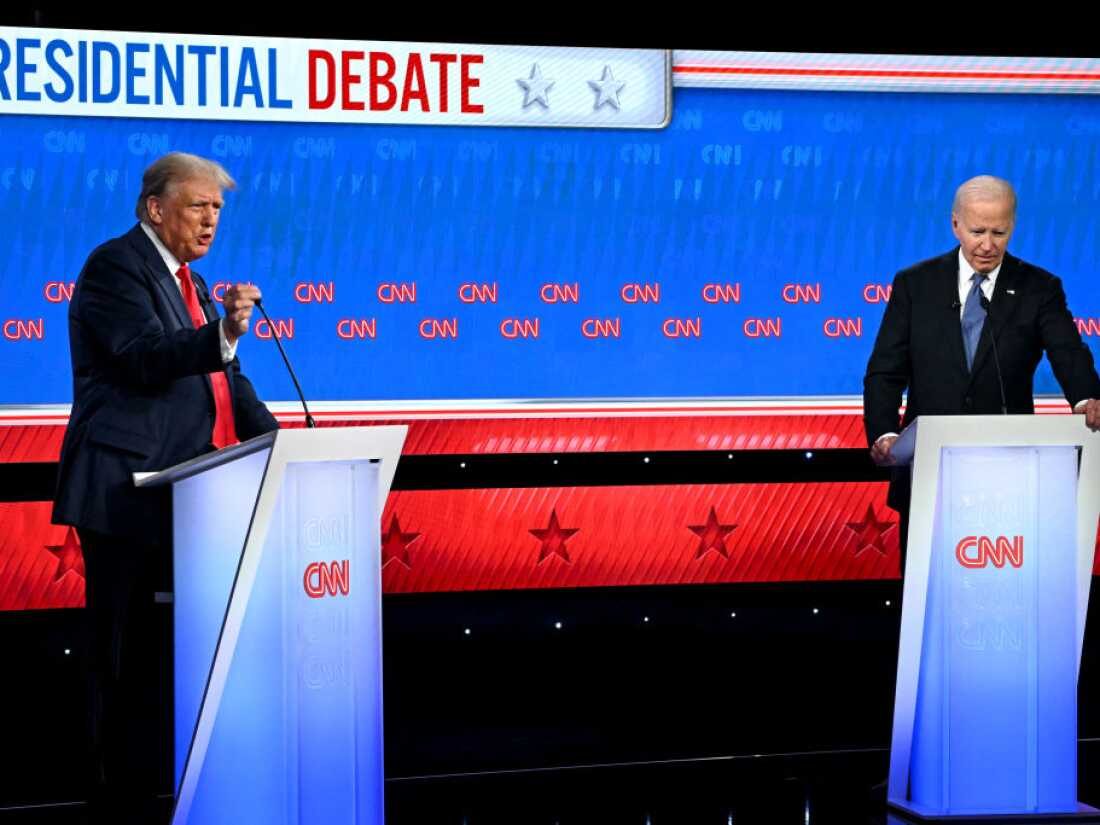 Two candidates at podiums on a televised debate stage