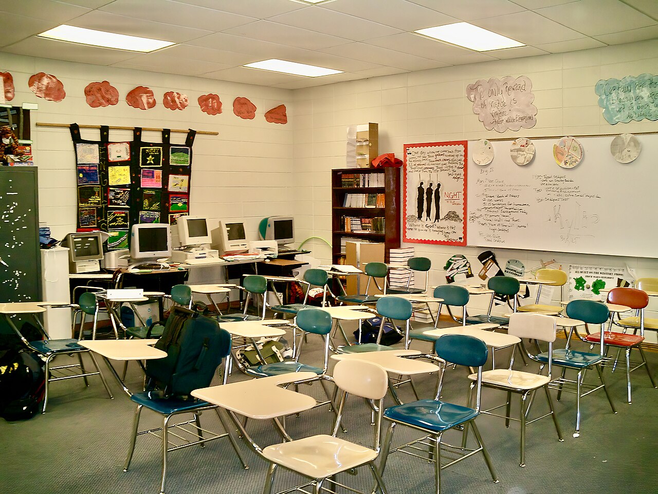 An empty high-school classroom with desks, computers, and a whiteboard