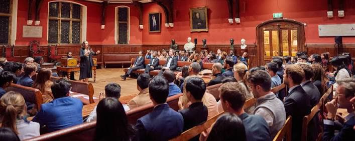 A speaker at the despatch box addressing a full chamber at the Oxford Union